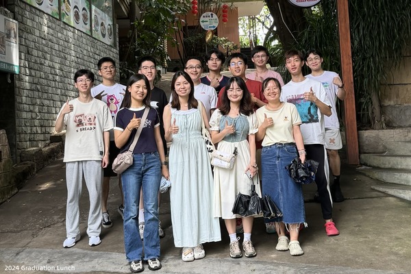 Lab members seated together around a table during a graduation gathering
