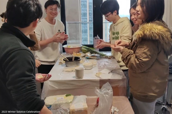 Lab members preparing food together around a table during a Winter Solstice gathering