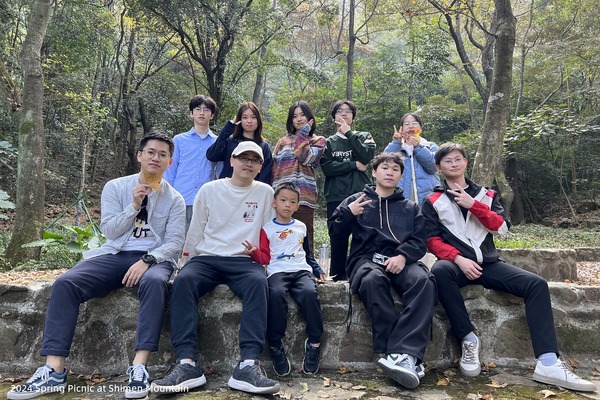 Lab members seated together beside a wooded trail during a spring outing
