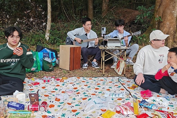 Lab members gathered on picnic mats while two people play guitars