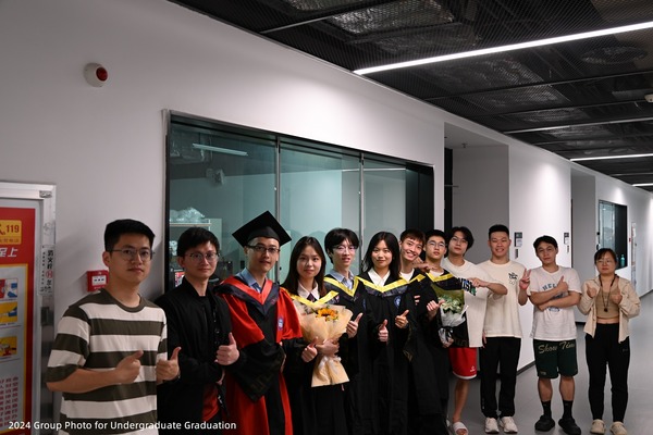 Lab members posing together outdoors with graduating undergraduate students