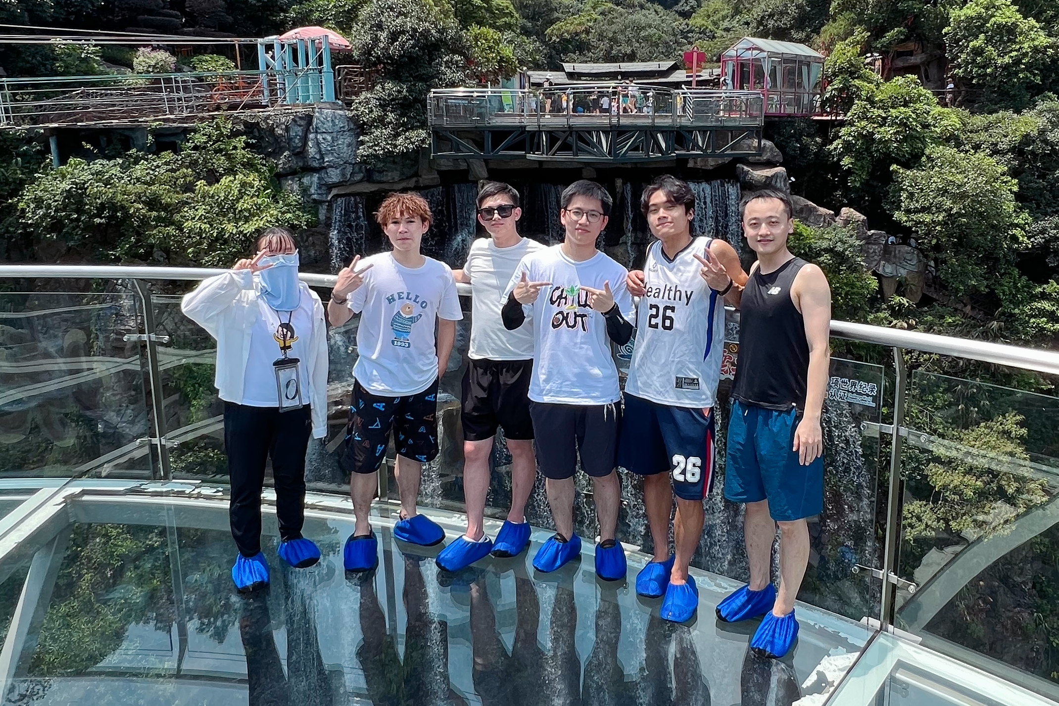 Six group members posing on a glass walkway surrounded by greenery during the Qingyuan outing.