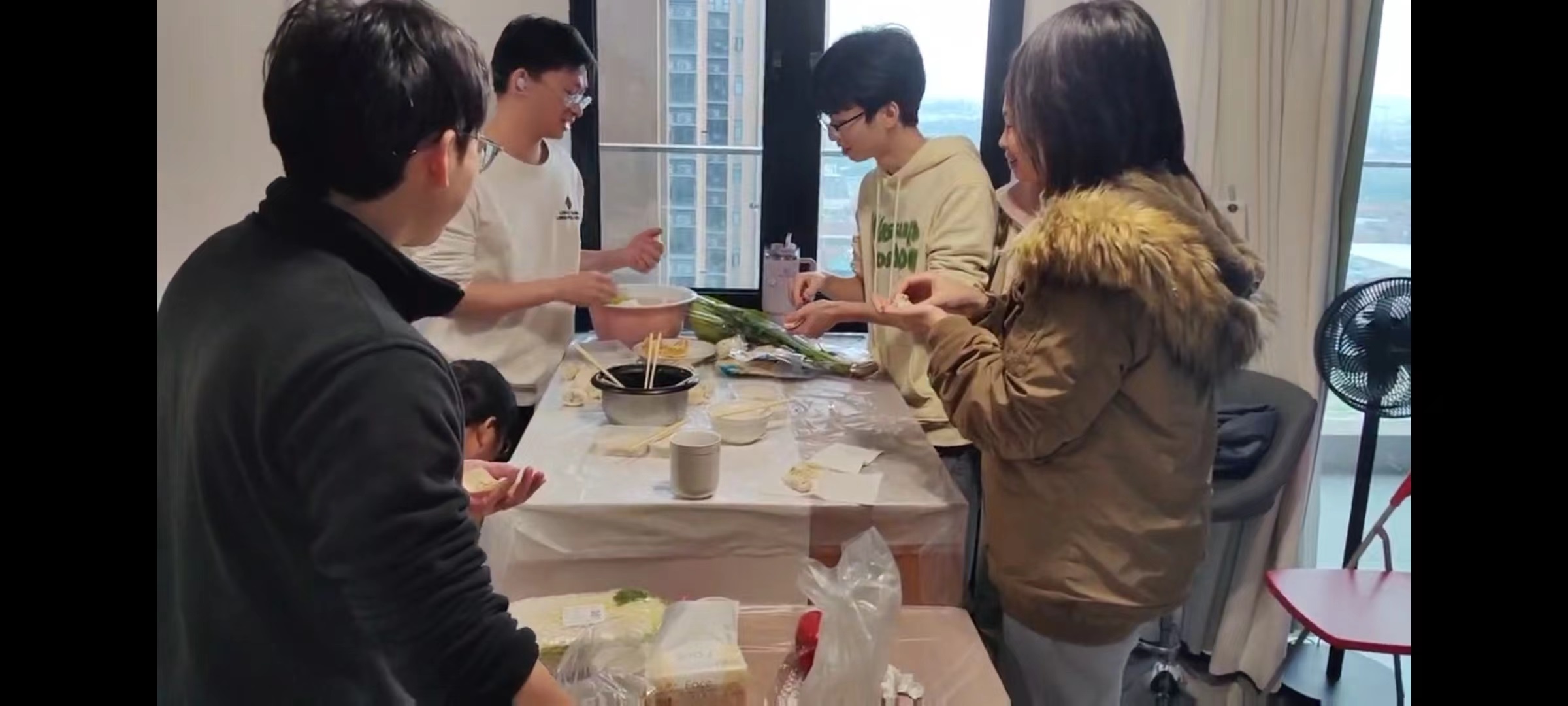 Group members preparing dumplings together around a table.