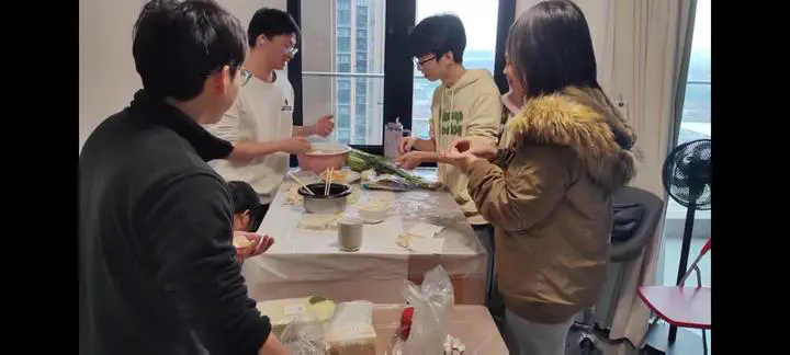 Group members preparing dumplings together around a table.